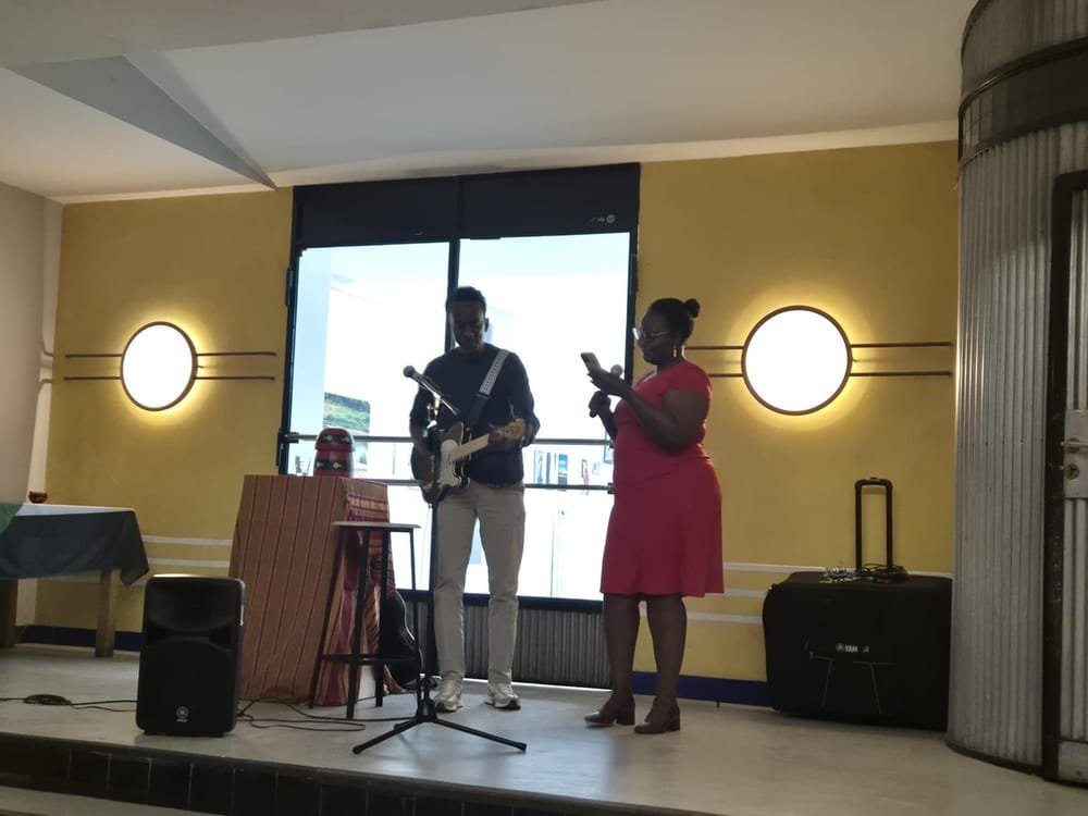 Live music during the exhibition: a man plays electric guitar on a small stage beside a woman in a red dress.